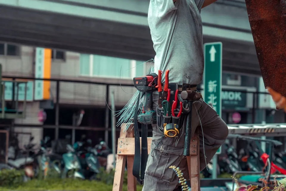 Handwerker mit Werkzeuggürtel auf einer Leiter